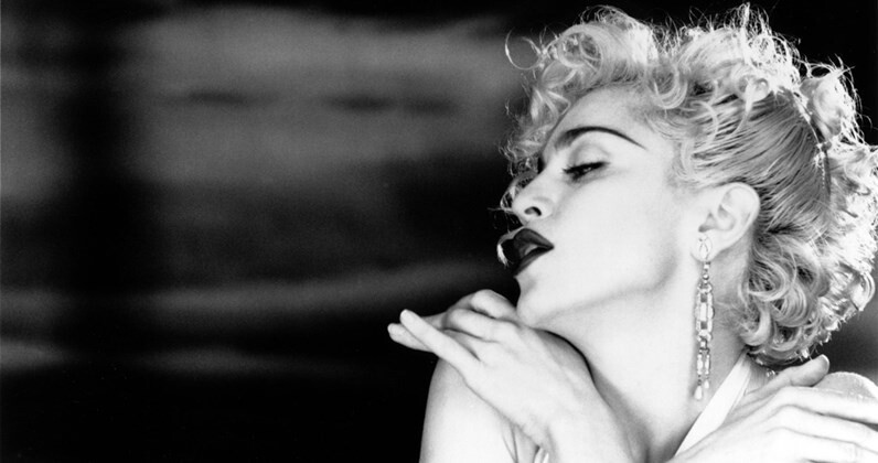 Madonna mandando beijinho no ombro em cena do clip de Vogue
