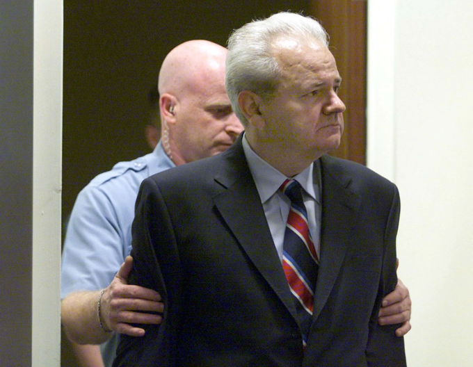 Slobodan Milosevic conduzido por guarda no Tribunal.