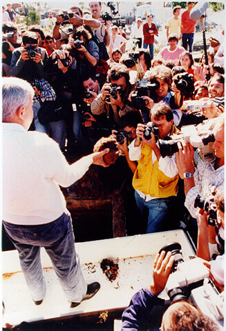 Cena macabra: o perito, sobre uma sepultura, exibe fragmentos de restos mortais a dezenas de jornalistas