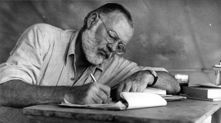 Foto em preto e branco de Hemingway escrevendo.