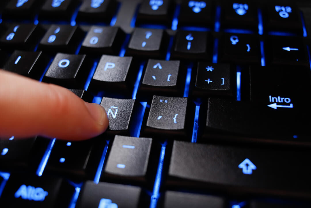 Dedo aciona tecla Ñ de um teclado espanhol
