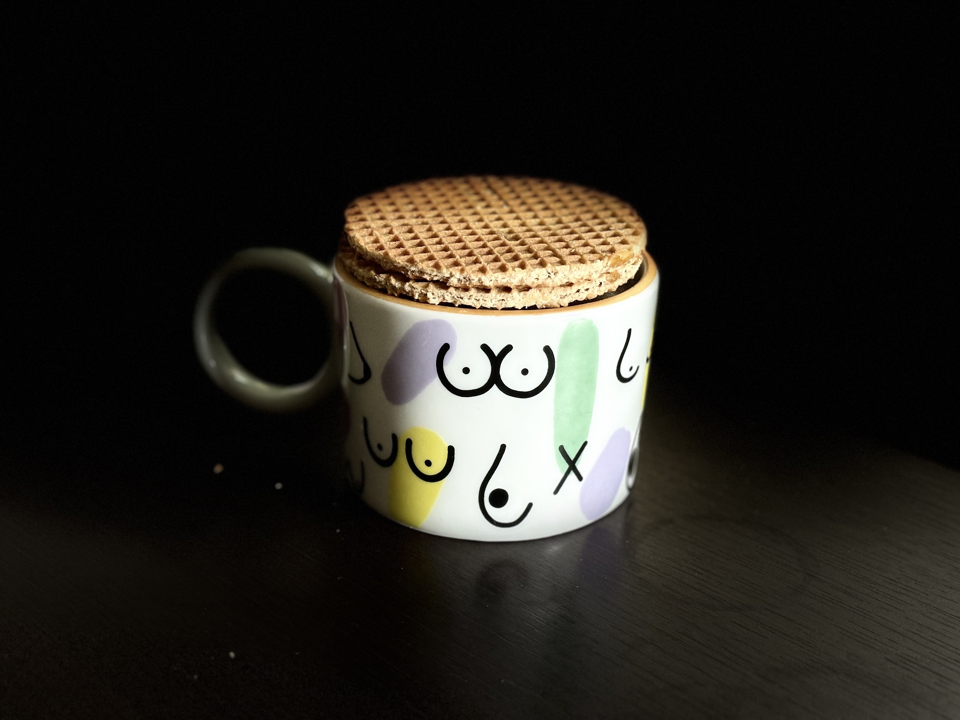 Dois biscoitos stroopwafel empilhados sobre uma xícara com desenhos de peitos