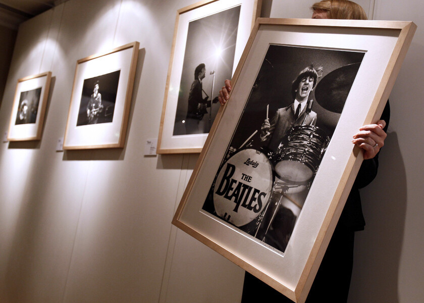 Foto de uma pessoa organizando quadros de uma exposição comemorativa dos 50 anos da chegada dos Beatles aos Estados Unidos, em Nova York.