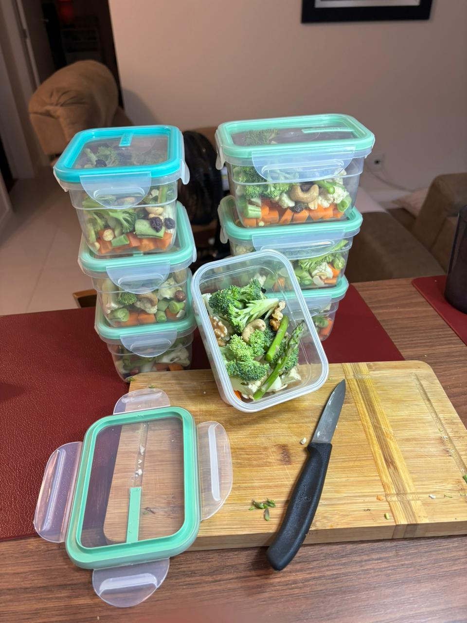 7 potes herméticos empilhados, cada um contendo legumes coloridos picados em cubos, algumas castanhas e sementes.