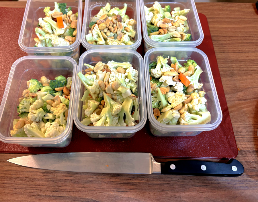 Uma faca de cozinha junto a 6 potes herméticos, ainda destampados, contendo legumes diversos, picados