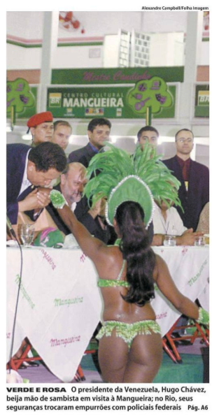 Em foto jornalística colorida, Chavez, de pé, beija a mão de uma passista que está de costas para a câmera usando uma fantasia carnavalesca em formato de biquíni. A legenda diz: “VERDE E ROSA – O presidente da Venezuela, Hugo Chávez, beija mão de sambista em visita à Mangueira