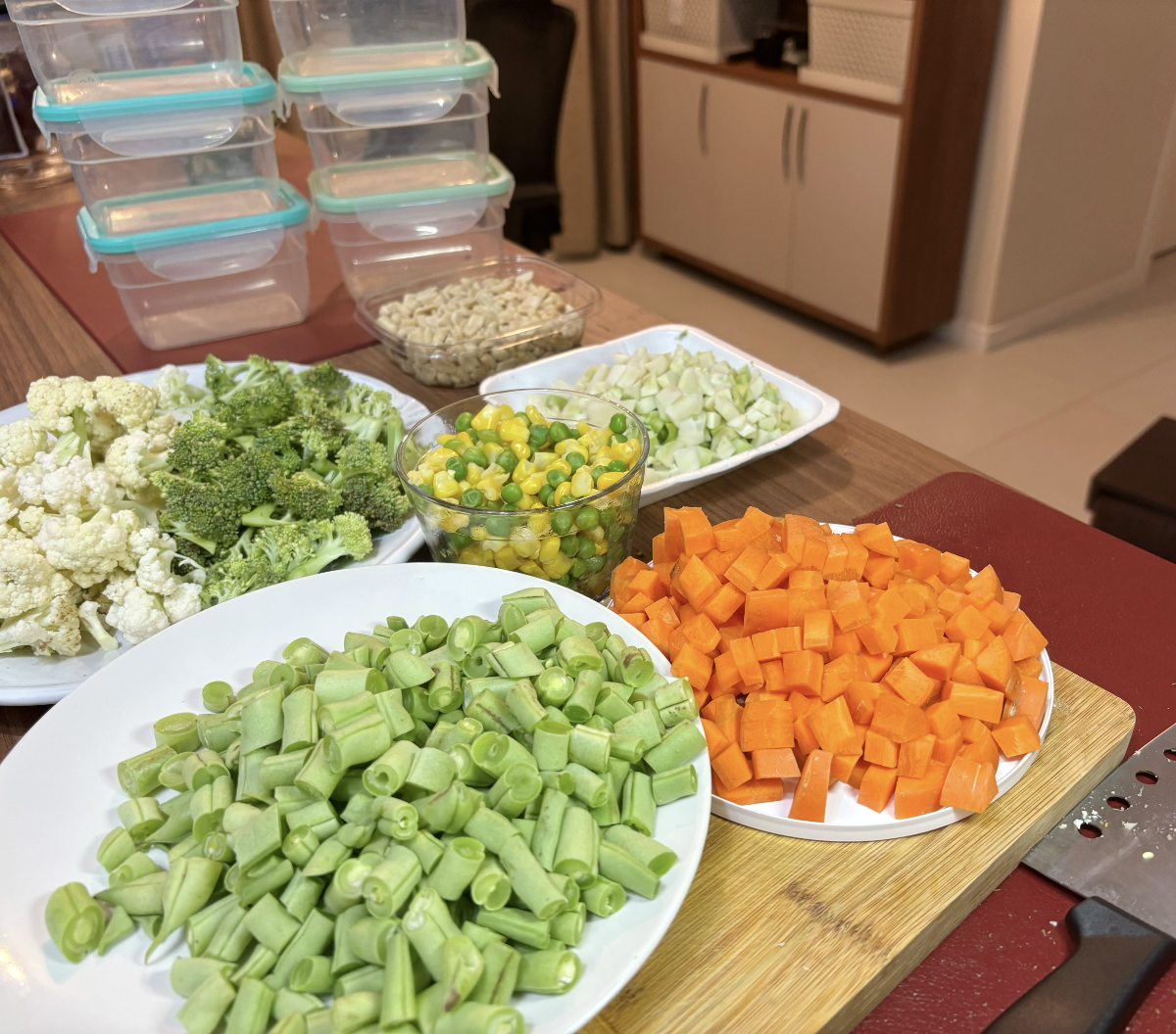 Pratinhos individuais contendo os legumes e cereais descritos no post (cenoura, vagem, couve-flor, brócolis, amendoim, milho e ervilha) e, ao fundo, 6 potinhos herméticos individuais ainda vazios.