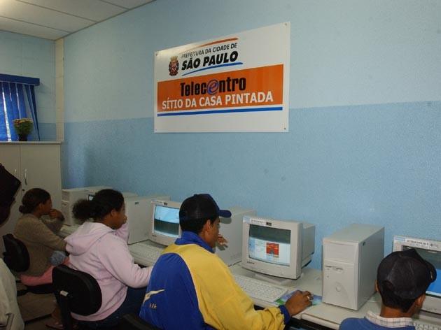 Pessoas operando PCs em um telecentro administrado pelo município de São Paulo