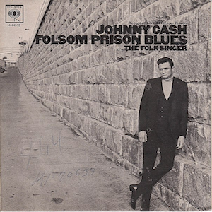 Capa da versão de 1955 do single de Folson Prison Blues mostra Johnny Cash escorado nos muros de uma prisão.
