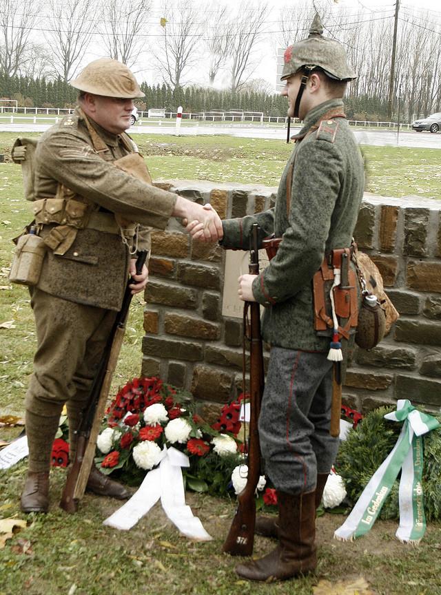 Descendentes de veteranos da guerra, em uniformes da época, apertando as mãos na inauguração de um memorial para a trégua (Frelinghien, França, 2008)