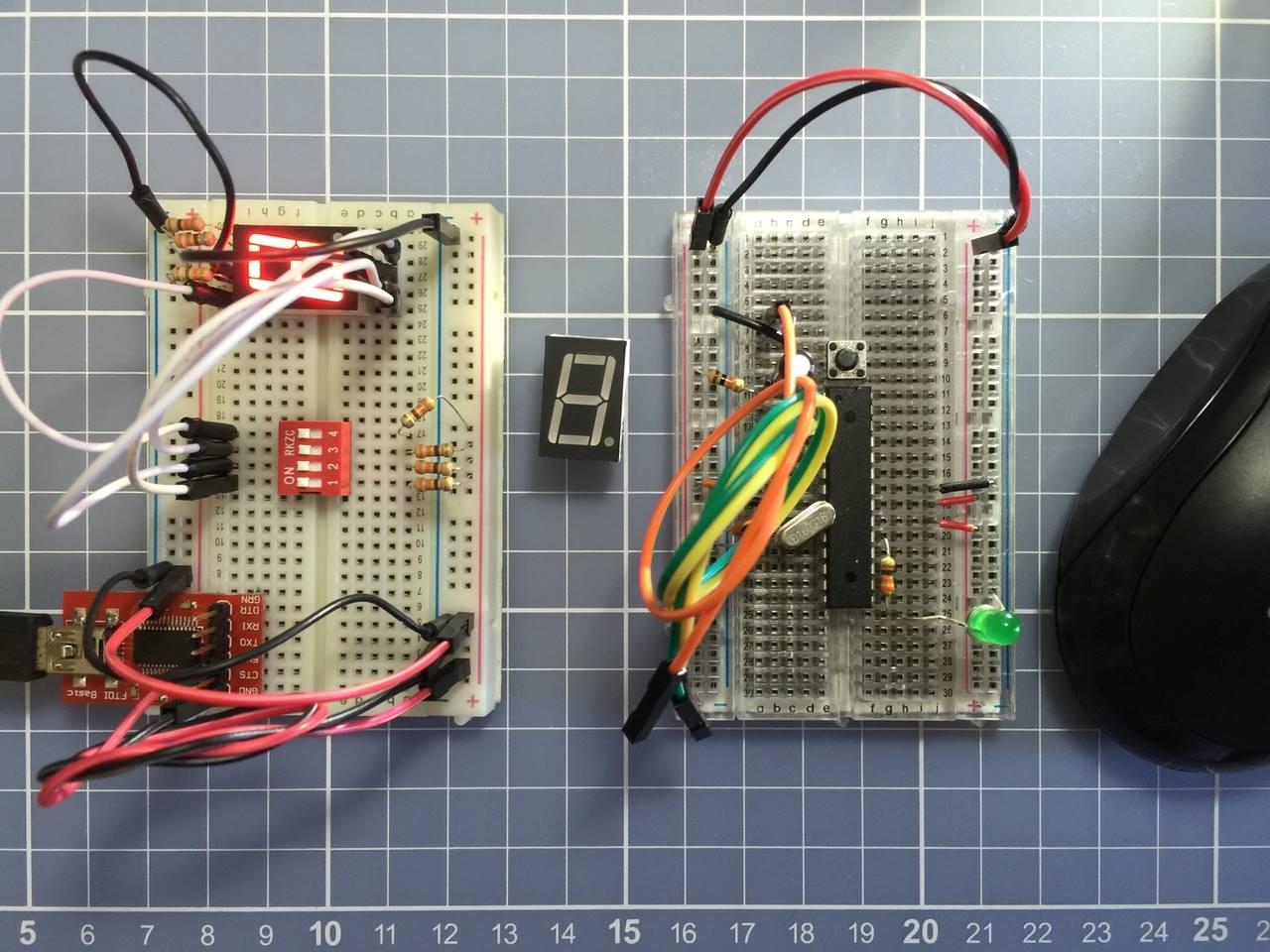 Foto de duas protoboards lado a lado, sendo que na da esquerda temos um circuito para controlar um display numérico usando dip switch, e na da direita temos a montagem do equivalente a um Arduino, com um microcontrolador e demais componentes mínimos.