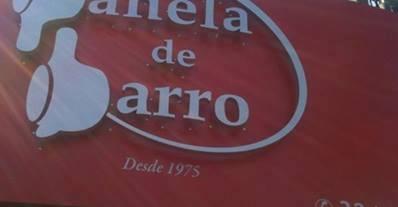 Fragmento da foto da fachada do restaurante Panela de Barro, cujas letras P e B são (mal) estilizadas na forma de desenhos de panelas viradas de lado.