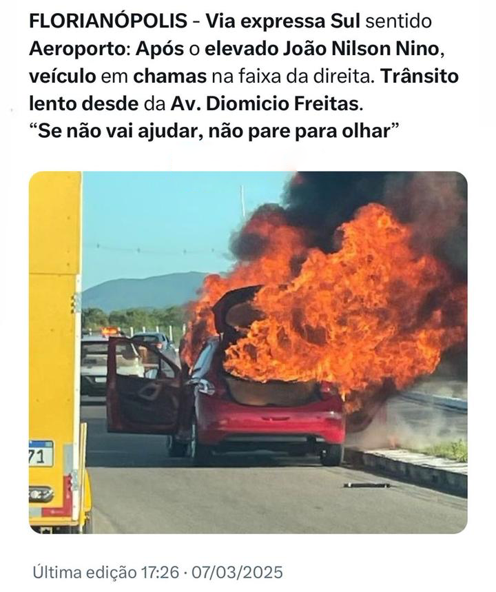 Foto de um carro vermelho, parado no acostamento e tomado por altas labaredas, datada de hoje às 17:26, com o texto: <br><br>FLORIANÓPOLIS - Via expressa Sul sentido Aeroporto: Após o elevado João Nilson Nino, veículo em chamas na faixa da direita. Trânsito lento desde da Av. Diomicio Freitas.“Se não vai ajudar, não pare para olhar“