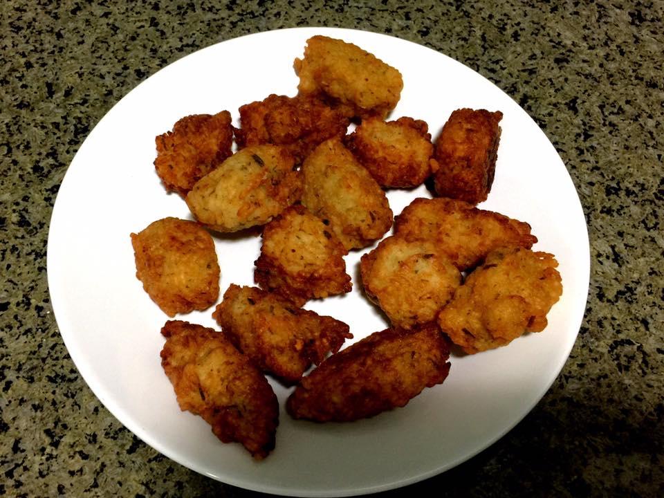 Um prato em cor branca contendo 15 bolinhos de arroz, já fritos e servidos.