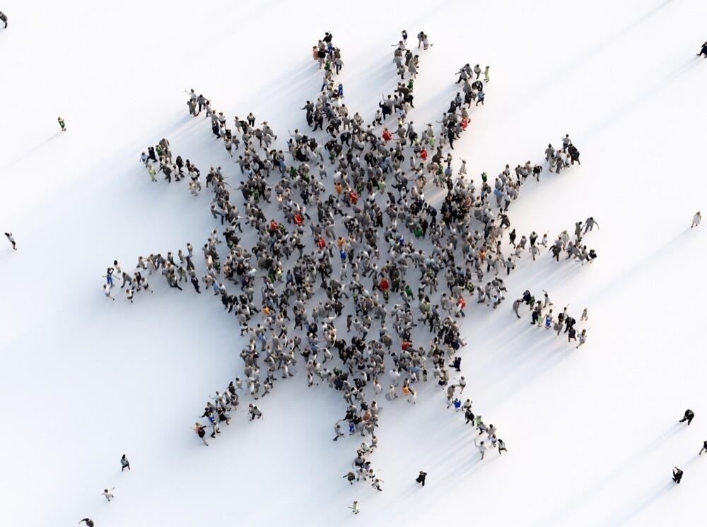 Montagem de um grande grupo de pessoas, visto de cima, formando a imagem de um vírus
