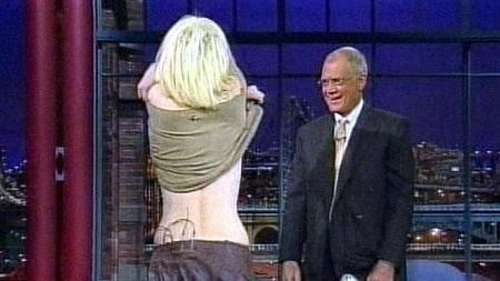 Foto de Courtney Love, de costas para a câmera, tirando o top no programa de David Letterman