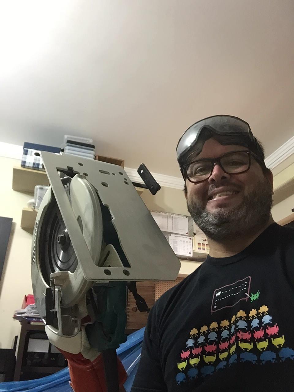 Foto minha segurando uma serra circular, com oculos de proteção e camiseta da academia dos space invaders